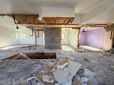 Interior of a building under extensive renovation with debris scattered.