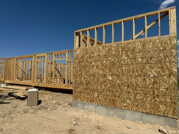 Wood-framed house under construction on a clear day.