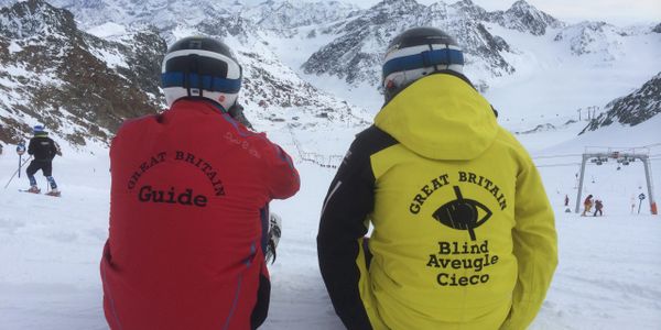 Pic taken from behind, JDL & Guide wearing GB ski jackets with mountains in background
