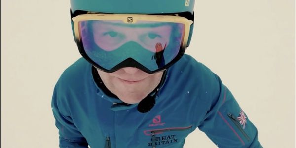 Pic of JDL skiing via helmet cam, showing his face, yellow googles & matching blue helmet/jacket