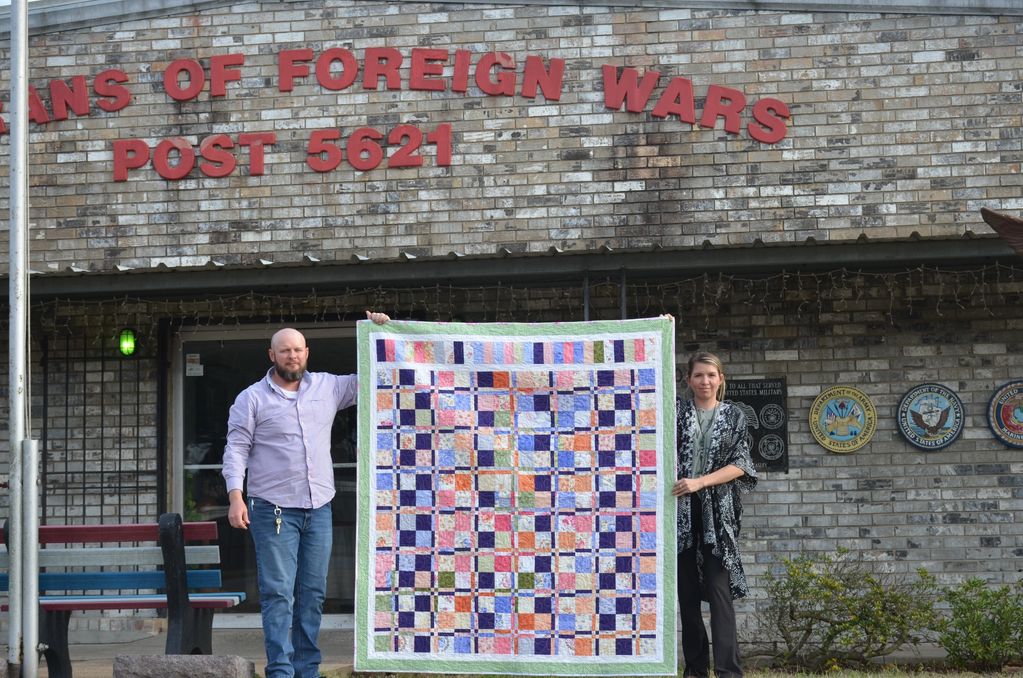 Commander Matthew Cooper and guest displaying quilt donated for a fundraiser