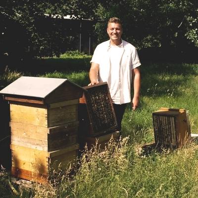 Max Mikat von beecologne - Imkerei Mikat steht neben neben zwei Firmenbienen Völkern