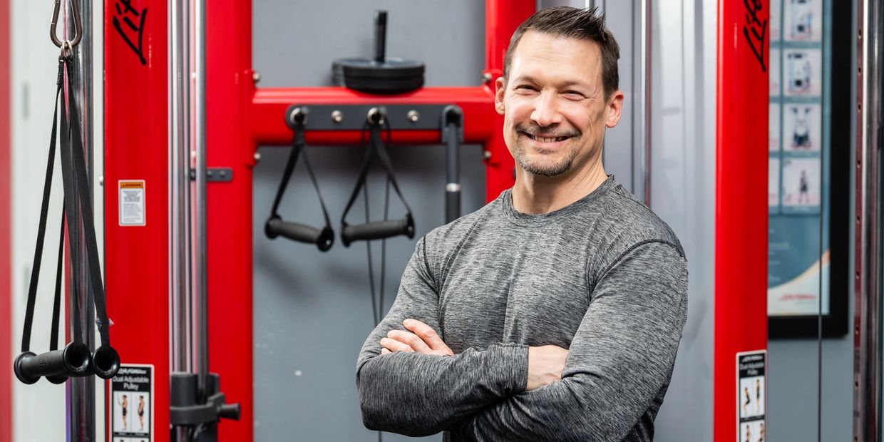 Jeff smiling at a gym with his arms crossed 