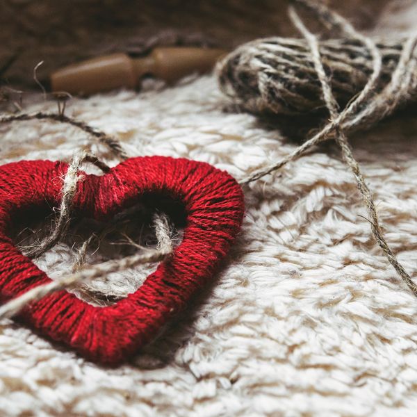 Red heart made of yarn on knitted fabric.