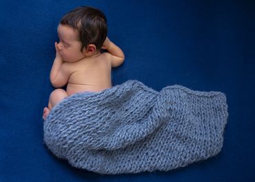 baby sleeping with blue blanket on blue background
