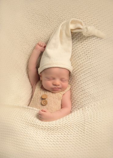 newborn wearing off  white hat on off white