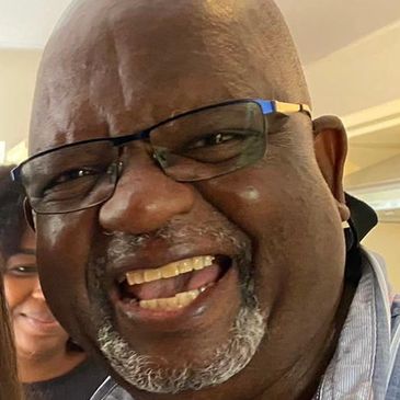 Close-up of a cheerful man with glasses laughing.