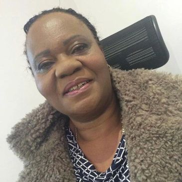 Woman smiling, wearing a brown fuzzy coat.