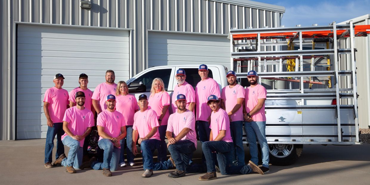 Team of workers in pink shirts posing by a truck.