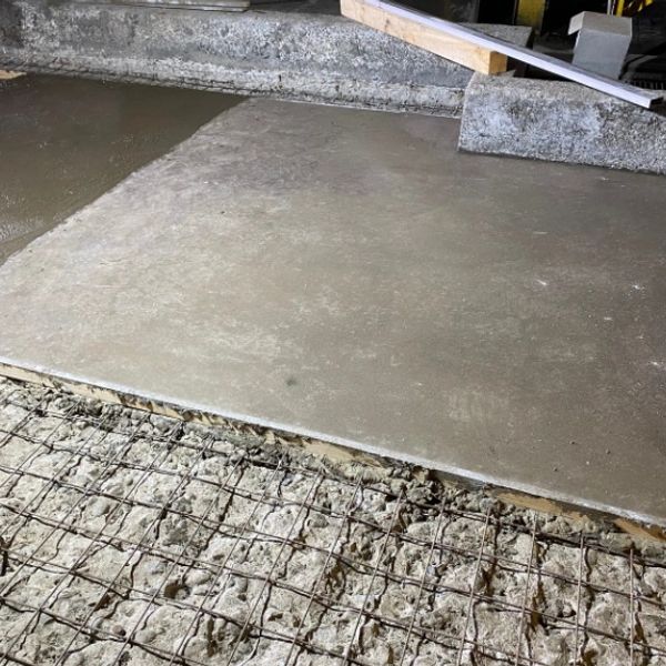 Freshly poured concrete slab with exposed wire mesh underneath.