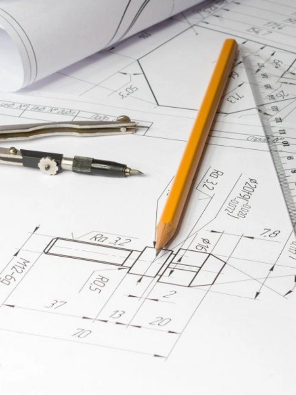 Technical drawing tools including pencil, compass, and ruler on engineering blueprint.