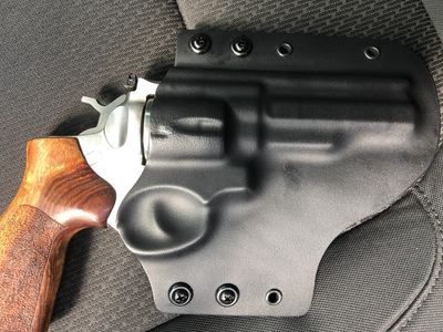 Revolver in a black holster on a car seat.