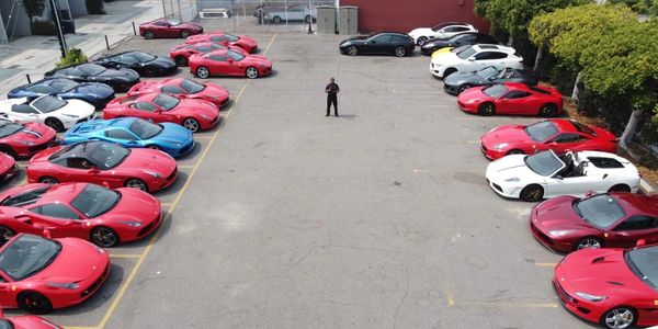 Multiple sports cars parked in a lot with a person in the middle.