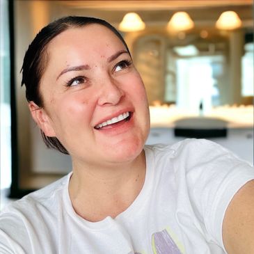 smiling female with dark hair and white t-shirt looking up