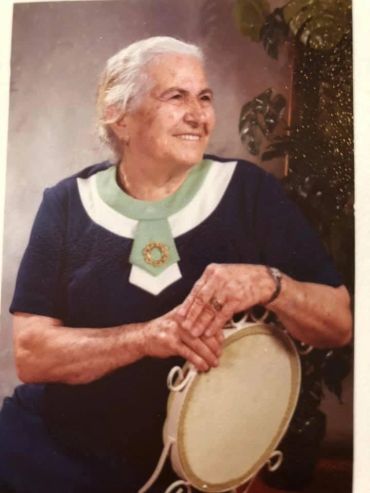 Elderly woman smiling and posing with a chair.