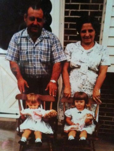 Two elderly adults with two young children holding dolls.