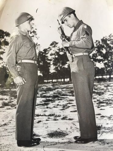 Two soldiers standing and saluting outdoors.
