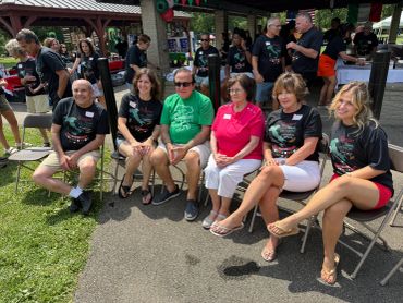 Group of people sitting outdoors at a casual event.
