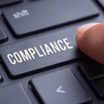 Finger pressing a keyboard key labeled 'COMPLIANCE'.