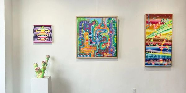 Three abstract paintings on a white gallery wall.