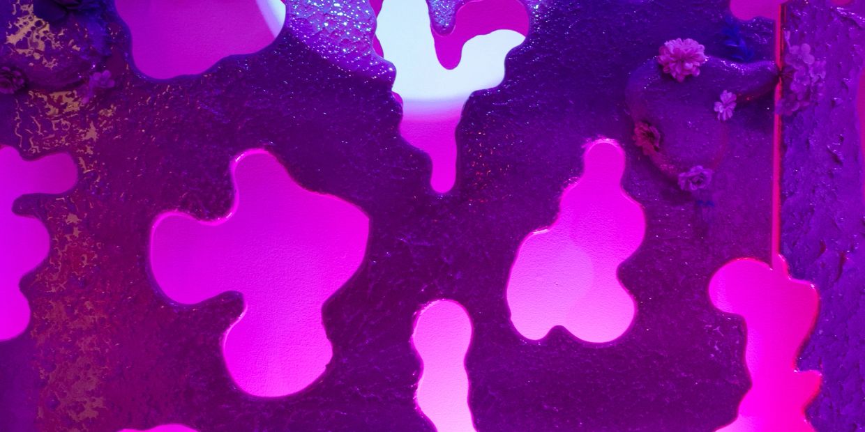 Abstract purple textured surface with heart-shaped cutouts and flowers.