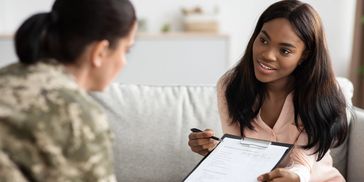A woman is helping a soldier fill out a psychology survey questionnaire.
