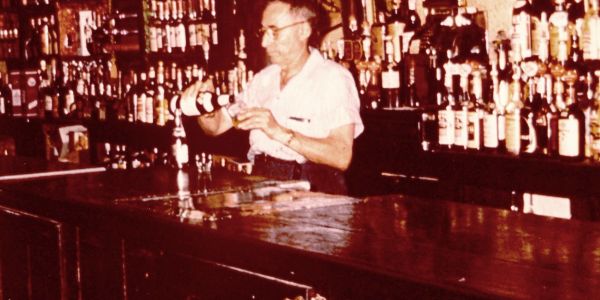 Bartender pouring a drink behind a bar.