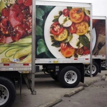 Truck murals align to create a continuous food image across trailers.