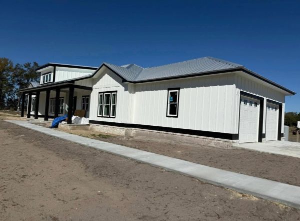 Newly built modern white house with a metal roof and large porch.