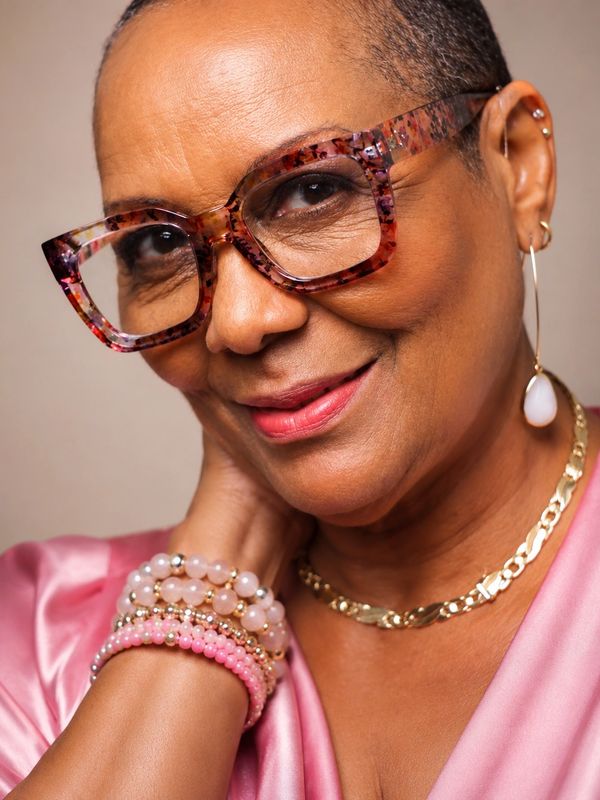Elegant woman wearing large glasses and pink accessories.