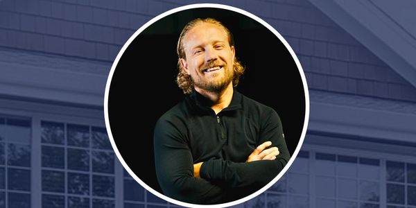 Smiling man with crossed arms in dark clothing.