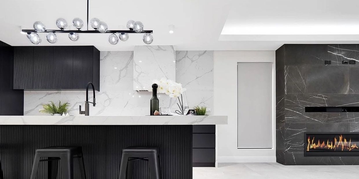 Modern kitchen with black accents, marble surfaces, and a sleek fireplace.