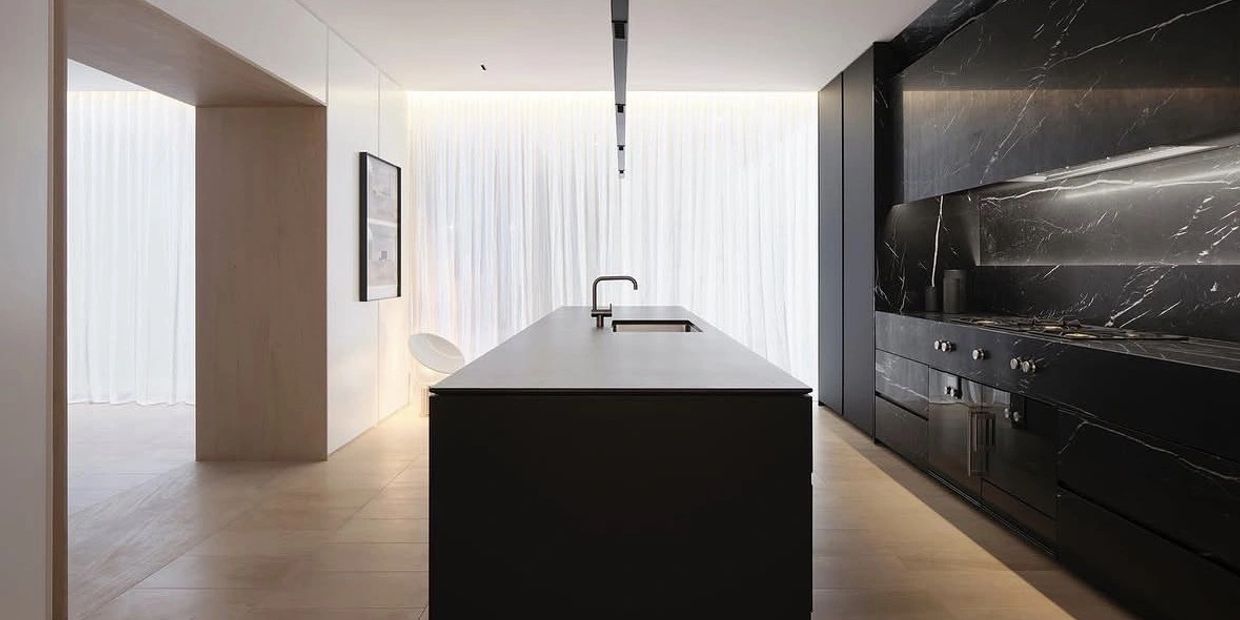 Minimalist kitchen with black marble surfaces and soft natural lighting.