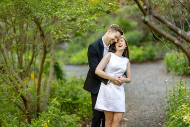 A couple embraces happily in a lush garden path.