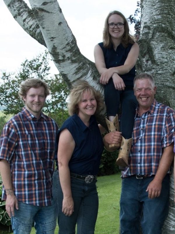 A family unit posing around a birch tree smiling!