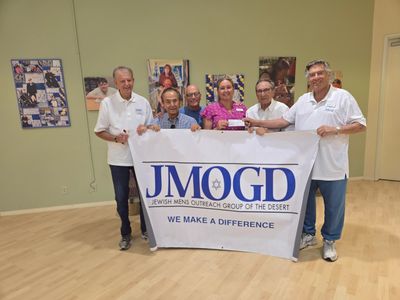 Group holding JMOGD banner promoting community impact.