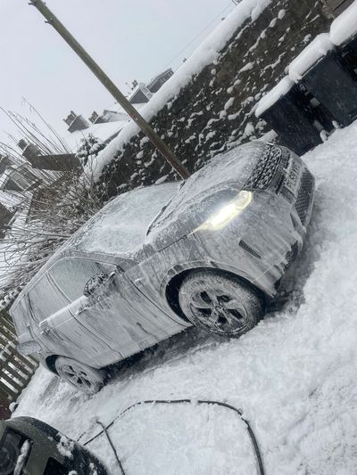 Car covered in snow and ice with headlights on.