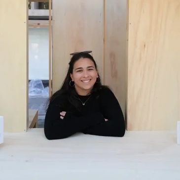 Smiling woman leaning on a wooden counter with a book on her head.