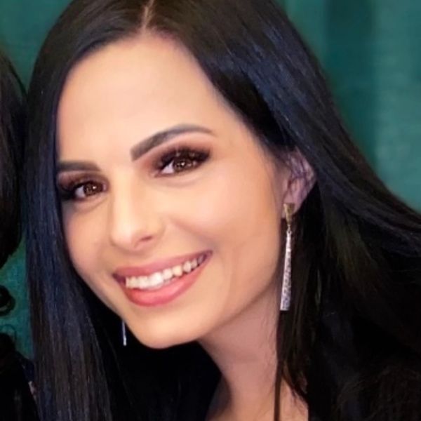 Smiling woman with long black hair wearing earrings.