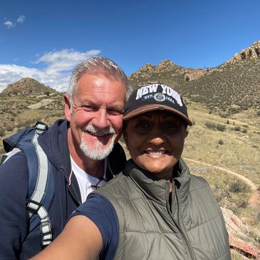 Smiling couple hiking on a sunny day in a mountainous area.