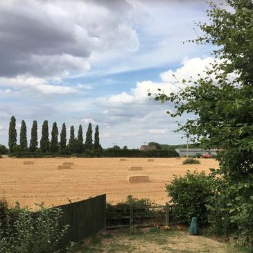 Rural field with hay bales under a partly cloudy sky.
