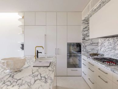 Modern kitchen with marble countertops and sleek white cabinetry.