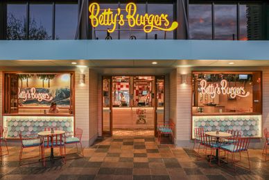 Exterior of Betty's Burgers restaurant with outdoor seating and neon signage.