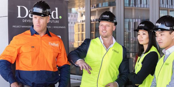 Four construction workers wearing safety gear and hard hats at a project site.