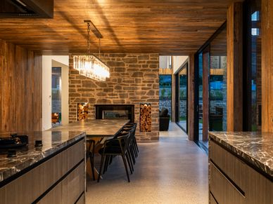 Modern dining room with wooden accents and stone fireplace.