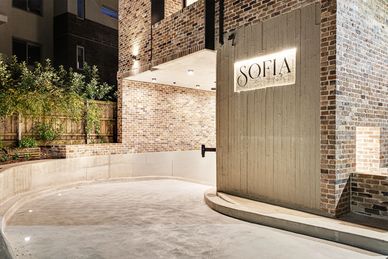 Entrance of a building named SOFIA with brick walls and outdoor lighting.