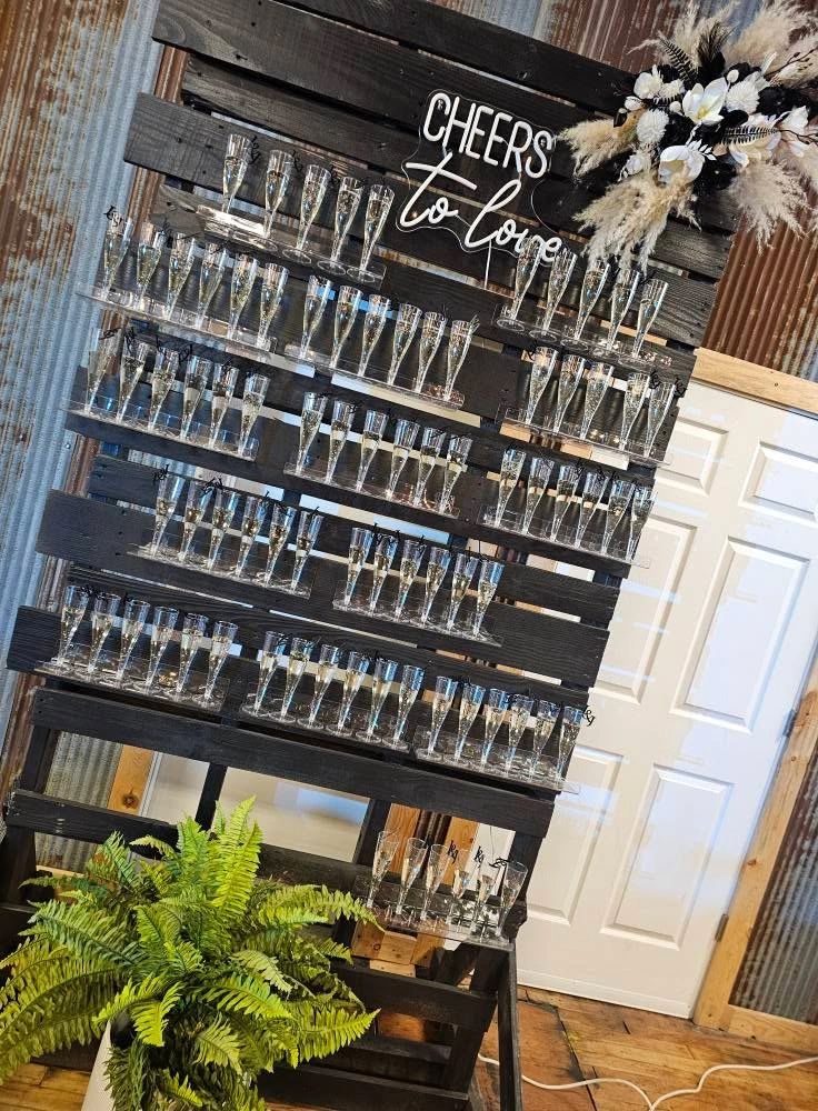 Champagne glasses on a rustic wooden display with "Cheers to love" sign.