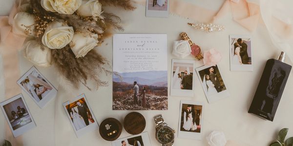 A flat lay of wedding items including photos, rings, flowers, and invitations.
