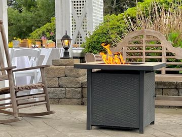 Outdoor patio with a fire pit table and rocking chair.