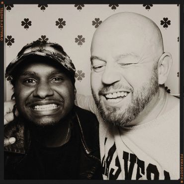 Two friends smiling in a playful black and white photo booth picture.